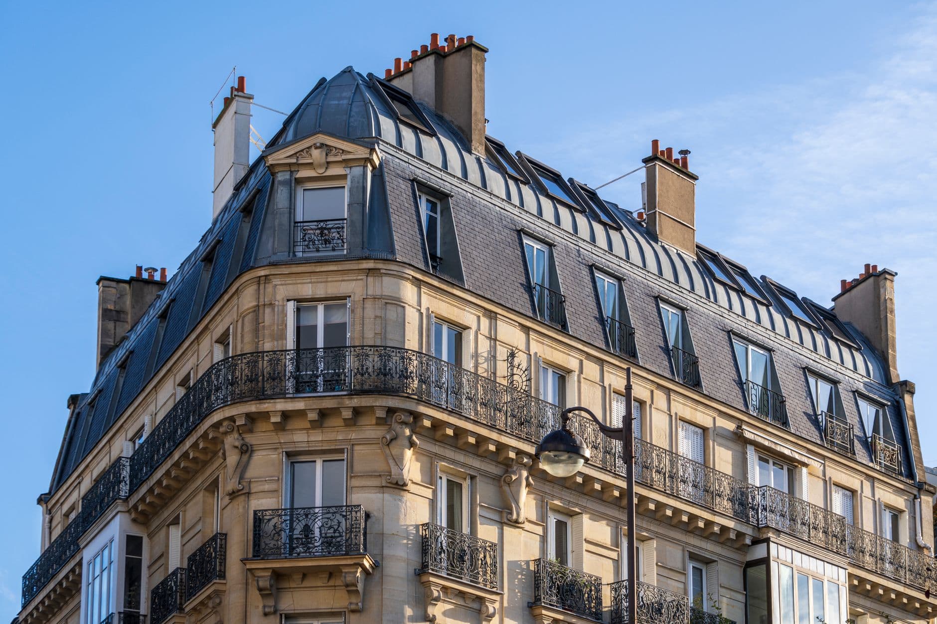 Immeuble haussmannien parisien à l'angle de deux rues, avec ses balcons en fer forgé.
